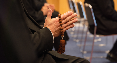 praying hands holding a rosary