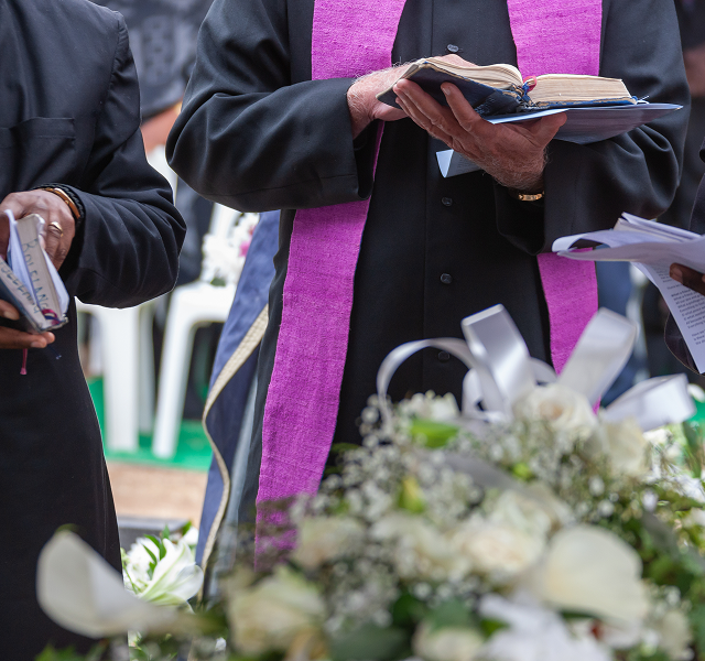 priest holding an open Bible during a service